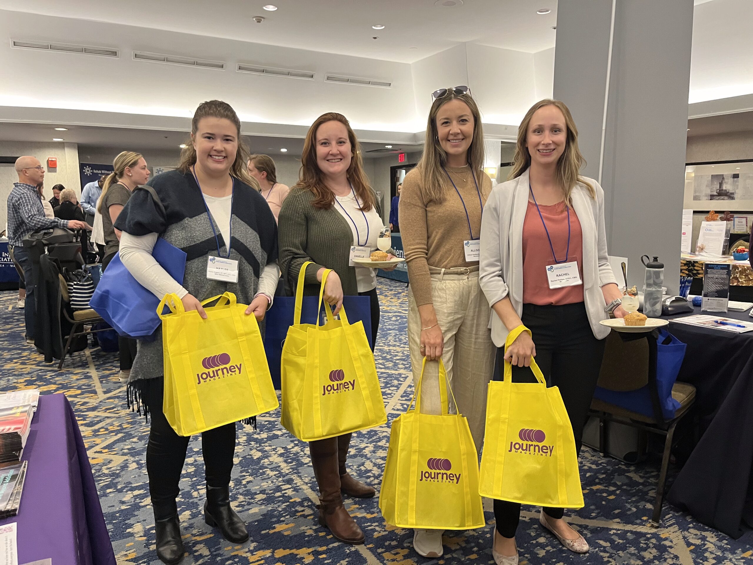 Journey team members at a community outreach event with branded yellow tote bags